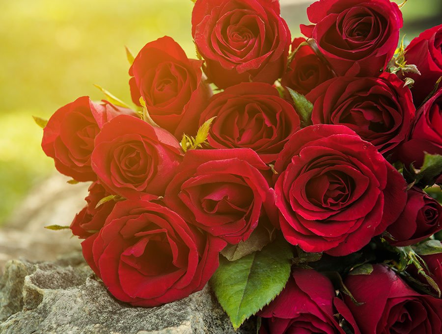 Ramo de rosas rojas sobre mesa de piedra.