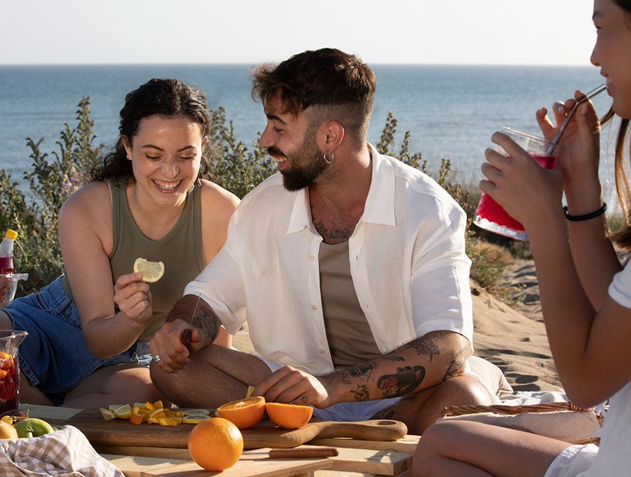 Amigos comen fruto en un pícnic junto al mar.