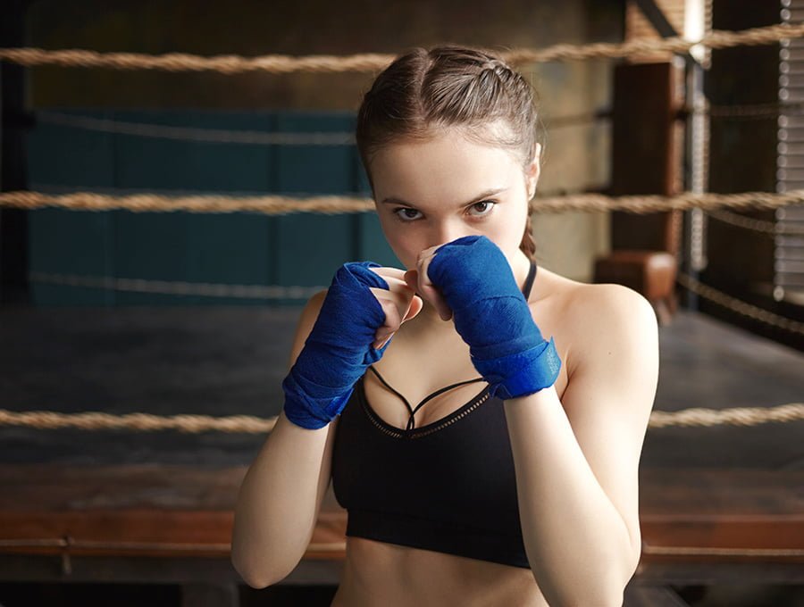 Chica con guantes de boxeo entrenando en el ring.