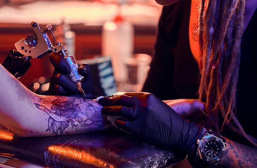 Tatuadora experta realiza un tatuaje en el brazo de un cliente.
