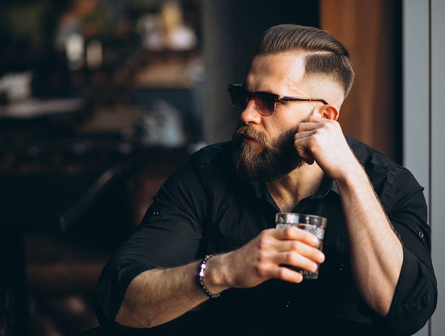 Hombre con barba tomando un refresco en el bar.