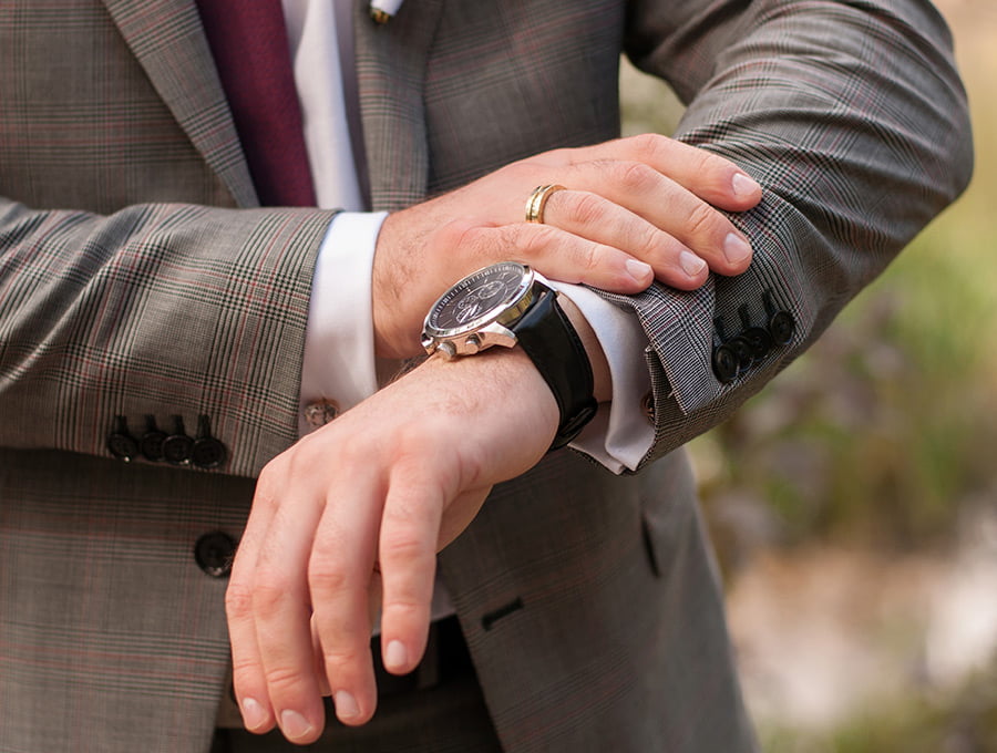 Hombre trajeado mirando su reloj de pulsera.