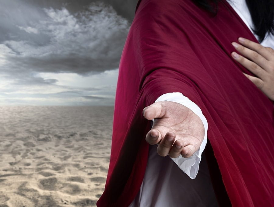 Jesucristo con la mano abierta caminando por el desierto en medio de la tempestad.