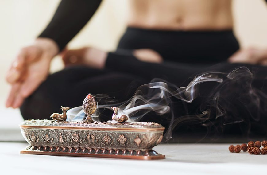 Mujer practica posturas de yoga y meditación, junto a su portaincienso de latón.