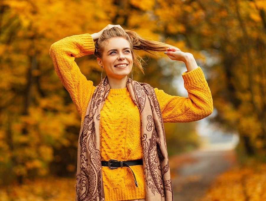Mujer con ropa amarilla dando un paseo por el bosque durante el otoño.