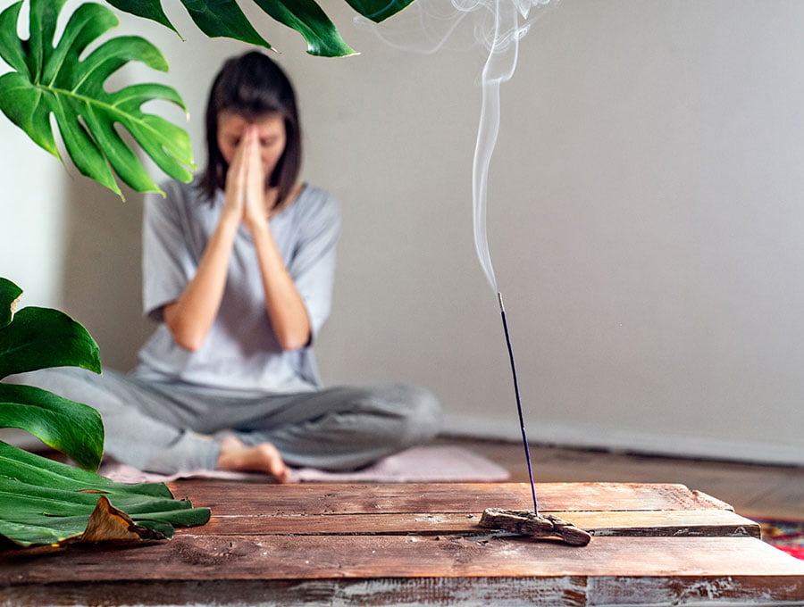Mujer ha encendido una varita de incienso de cedro para meditar y practicar yoga.