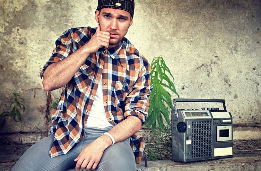 Hombre con camisa junto a radio antigua.