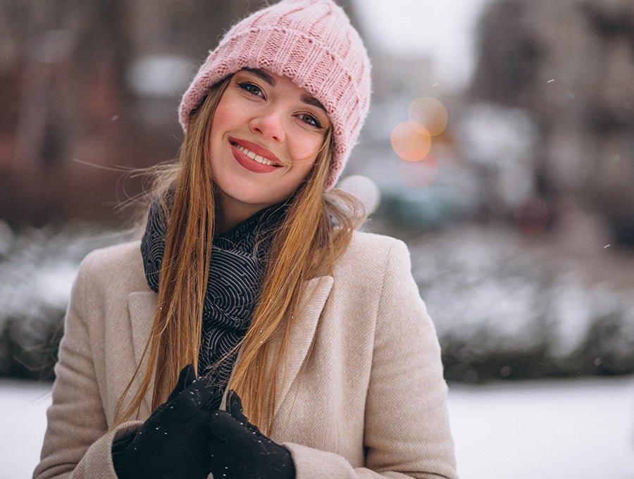 Mujer sonriente con gorro rosa de invierno.