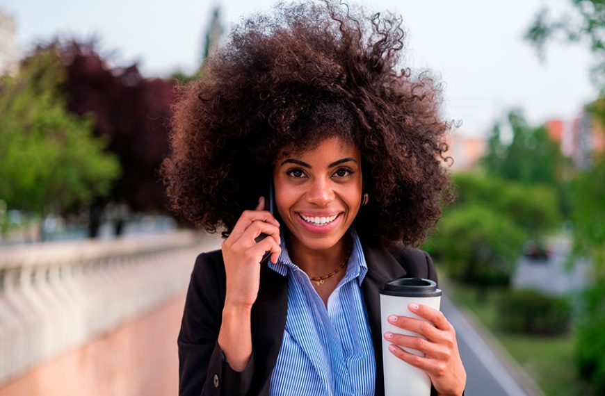 Mujer con pelo afro habla por teléfono.