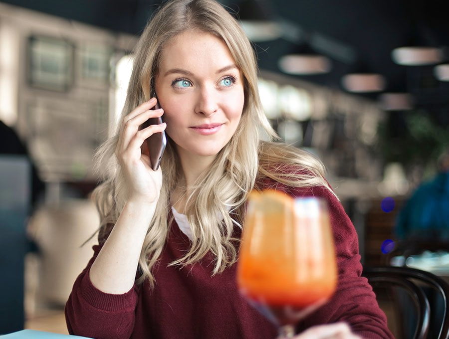 Mujer se toma un zumo mientras habla por teléfono.
